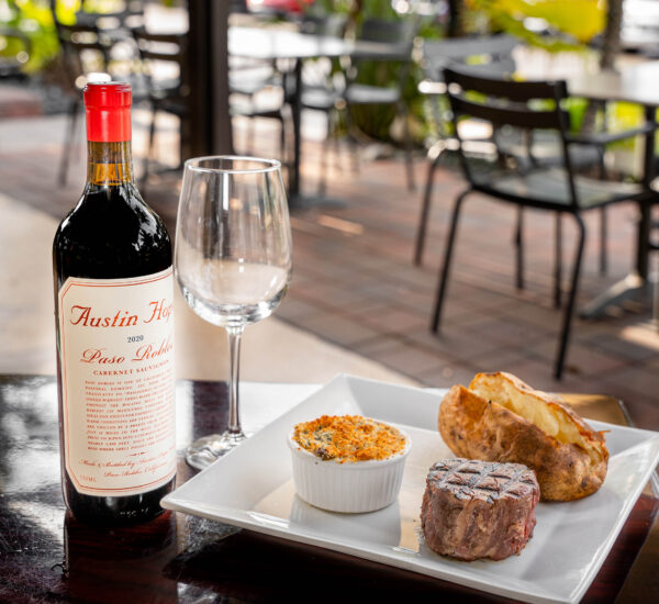 Steak and loaded potato with bottle of red wine